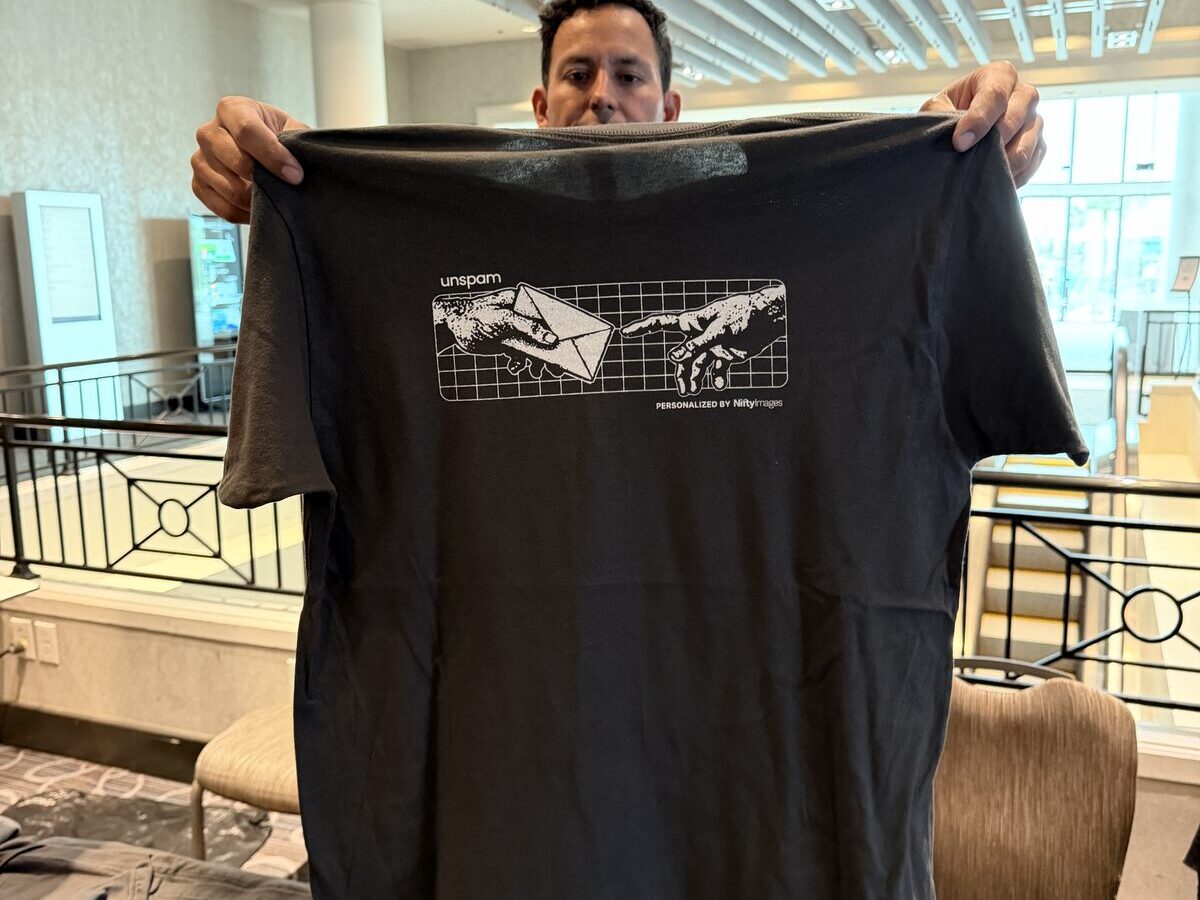 Event guest holding up a finished custom-printed dark t-shirt indoors